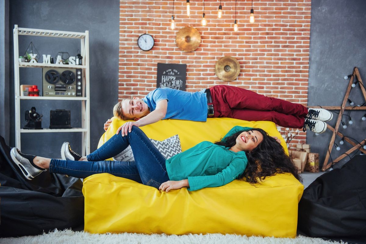 two Beautiful people, male and woman lying on a yellow sofa, in house.